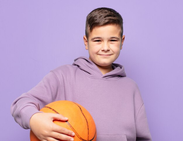 Niño feliz expresión y sosteniendo una pelota de baloncesto