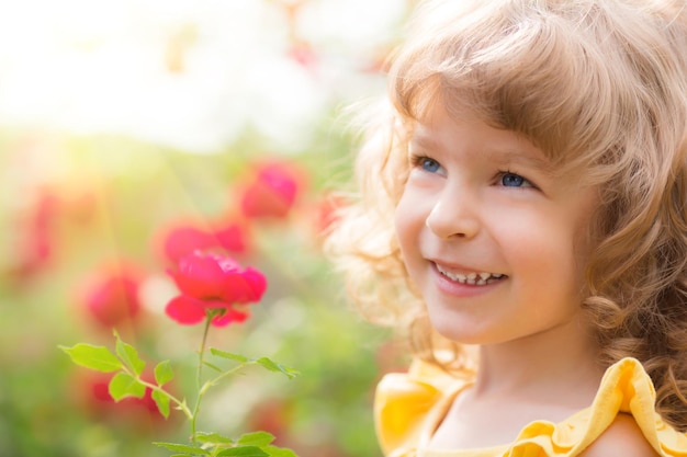 Niño feliz con flor al aire libre en el jardín de primavera