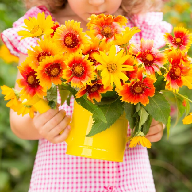 Niño feliz con flores al aire libre en el jardín de primavera