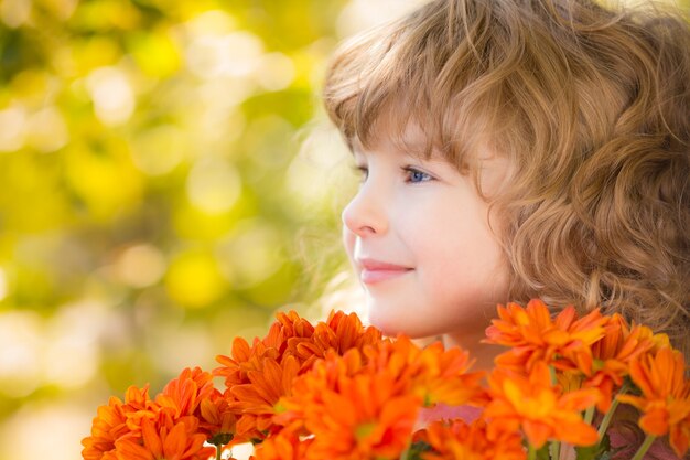 Niño feliz con flores al aire libre en el parque otoño