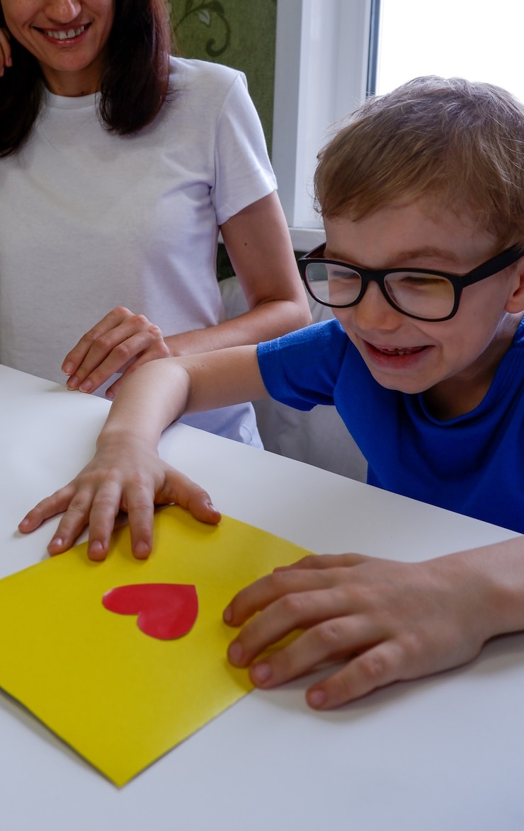 Foto un niño feliz con gafas hizo una tarjeta con sus propias manos para el día de san valentín, el día del padre.
