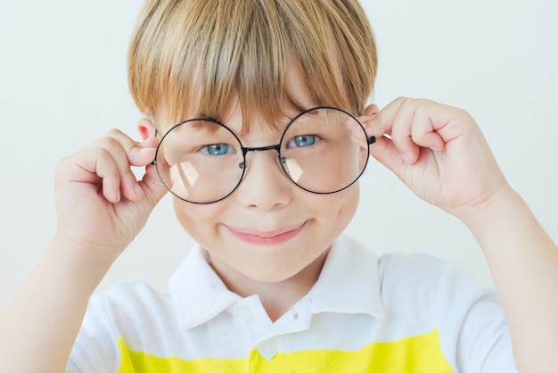 Niño feliz con gafas sobre fondo blanco.