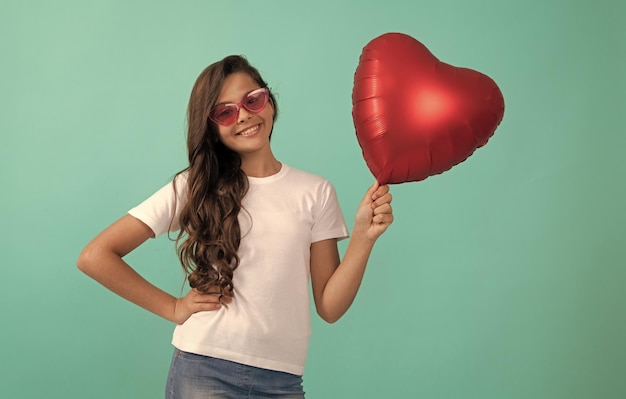 Niño feliz con gafas de sol con globo de fiesta rojo para el día de san valentín símbolo de amor venta de san valentín