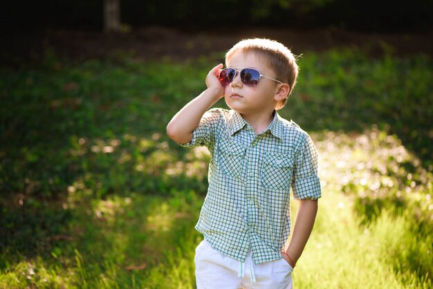 Niño feliz con gafas de sol en el jardín.