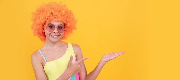 Niño feliz con gafas de sol señalando con el dedo sobre fondo amarillo copia espacio promoción Adolescente divertido