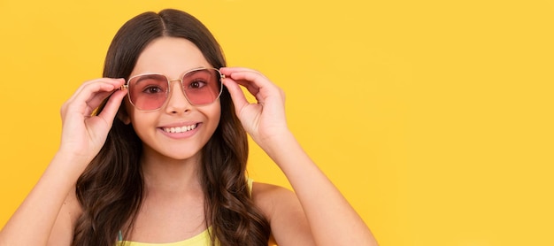Niño feliz en gafas de verano tiene pelo rizado sobre fondo amarillo moda de playa Cara de niño cartel horizontal adolescente chica aislada retrato banner con espacio de copia