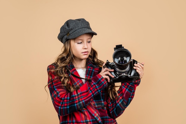 Niño feliz con gorra con peinado elegante, chaqueta a cuadros, cámara de fotos vintage para fotografiar