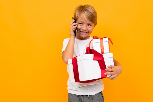 Niño feliz hablando por teléfono y sosteniendo una caja de regalo