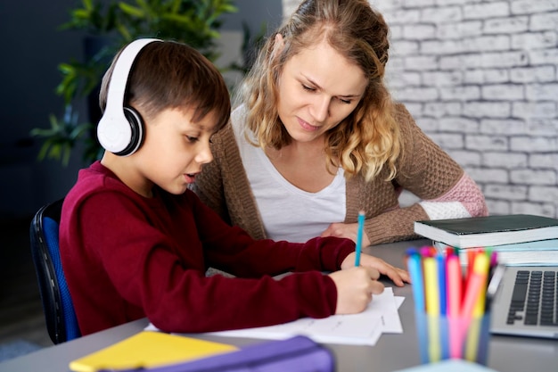 Niño feliz haciendo la tarea con su madre en casa