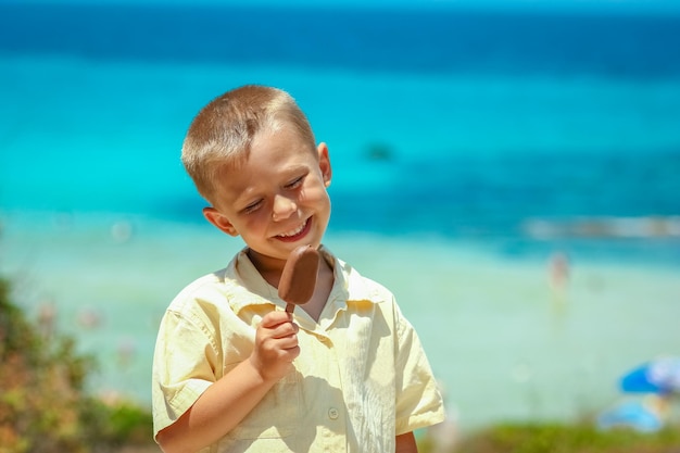 Un niño feliz con helado junto al mar en la naturaleza en el viaje del parque