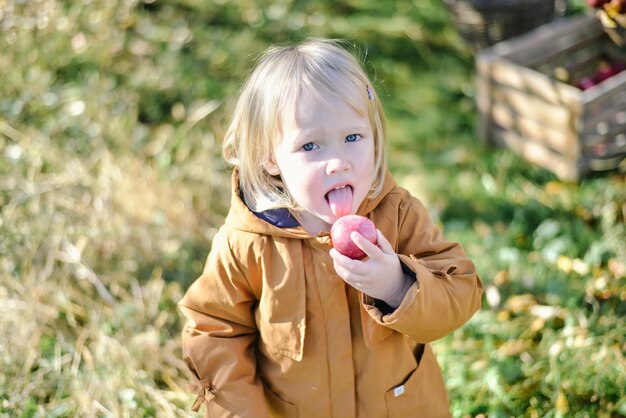 niño feliz en el jardín comiendo manzana orgánica roja