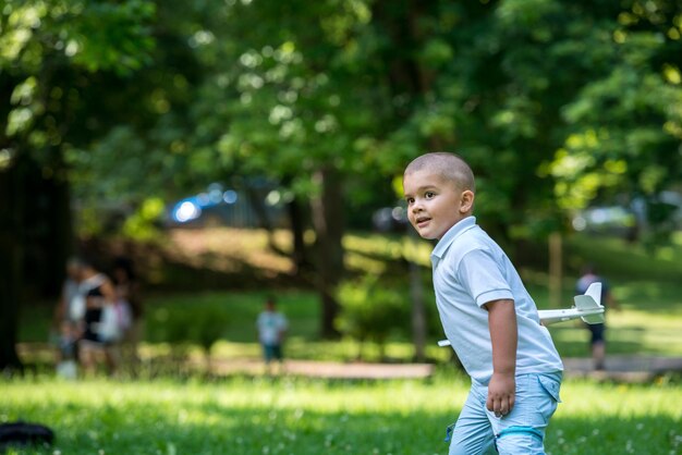 niño feliz juega y lanza juguetes de avión en el parque