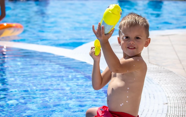 Niño feliz juega en la piscina con una pistola de agua