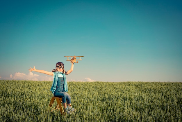 Niño feliz jugando con un avión de juguete al aire libre en el campo de verano Concepto de viajes y vacaciones Imaginación y libertad