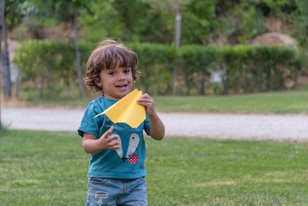 Niño feliz jugando con un avión de juguete contra el fondo del cielo de verano al atardecer