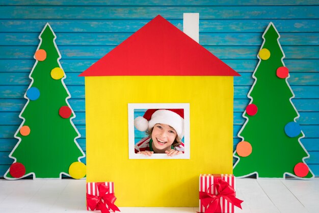 Niño feliz jugando en casa. Chico divertido en la víspera de Navidad