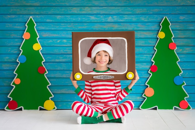 Niño feliz jugando en casa. Chico divertido en la víspera de Navidad