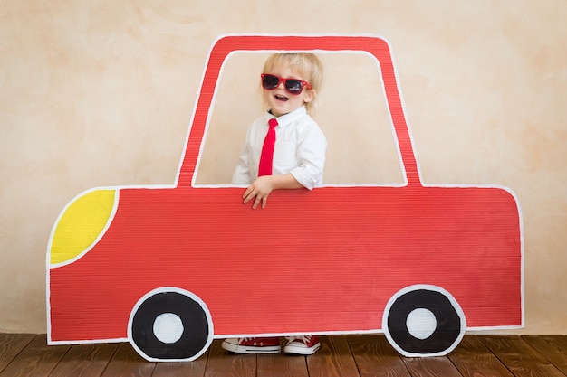 Foto niño feliz jugando con coche de cartón interior