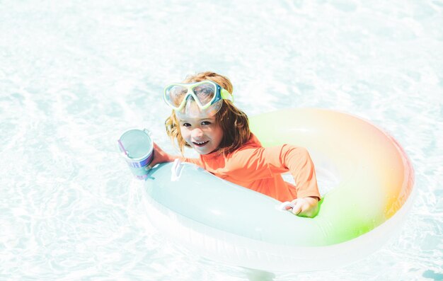 Niño feliz jugando con un colorido anillo de natación en la piscina en el día de verano Juguetes acuáticos para niños Los niños juegan en un resort tropical Vacaciones familiares en la playa