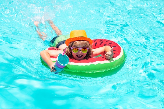 Niño feliz jugando con un colorido anillo de natación en la piscina en el día de verano niño agua vacaciones childr