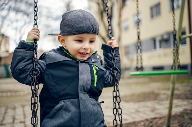 Un niño feliz jugando con columpio en un patio de recreo