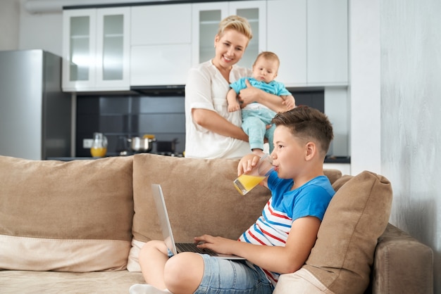 Niño feliz jugando en la computadora portátil mientras la madre sostiene al niño