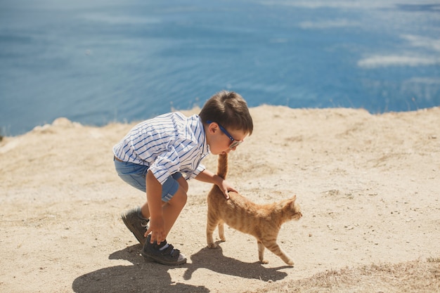 Niño feliz jugando con gato rojo.