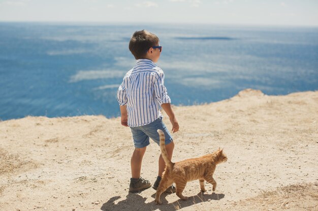 Niño feliz jugando con gato rojo.