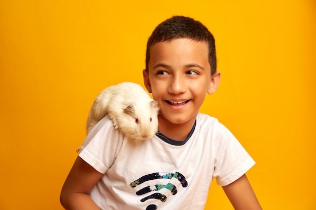 Foto niño feliz jugando con lindo conejillo de indias