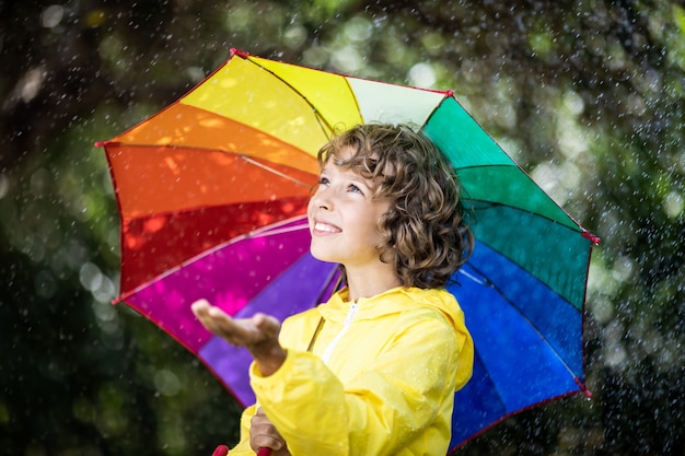 Niño feliz jugando bajo la lluvia