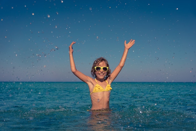 Niño feliz jugando en el mar. Niño divirtiéndose en las vacaciones de verano. Concepto de estilo de vida activo y saludable