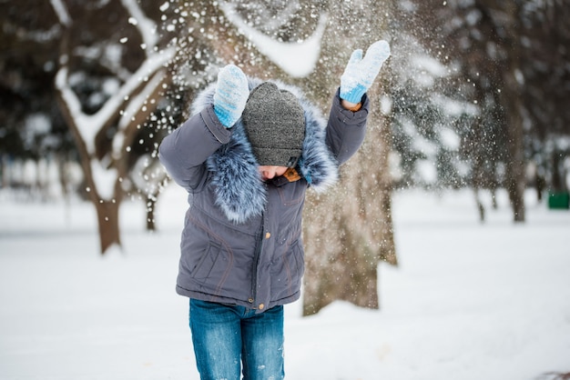 Niño feliz jugando en la nieve, juegos de invierno