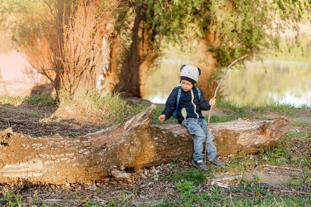 Niño feliz jugando en tocón de madera durante el paseo en el bosque