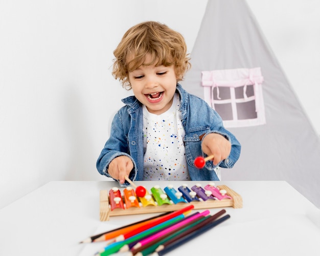 Foto niño feliz jugando con xilófono