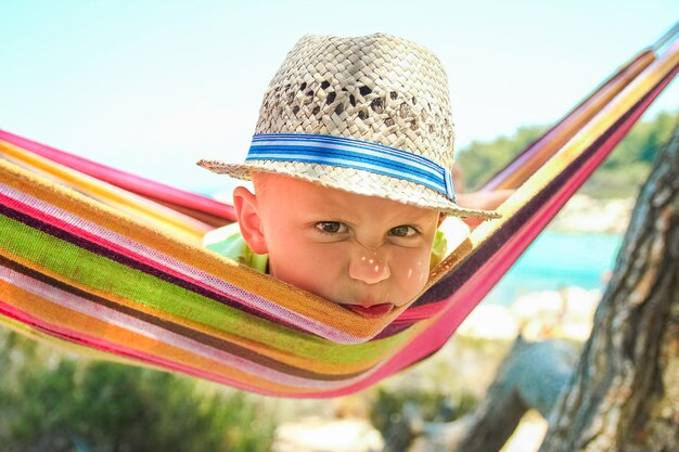 Niño feliz junto al mar en una hamaca en el fondo de Grecia