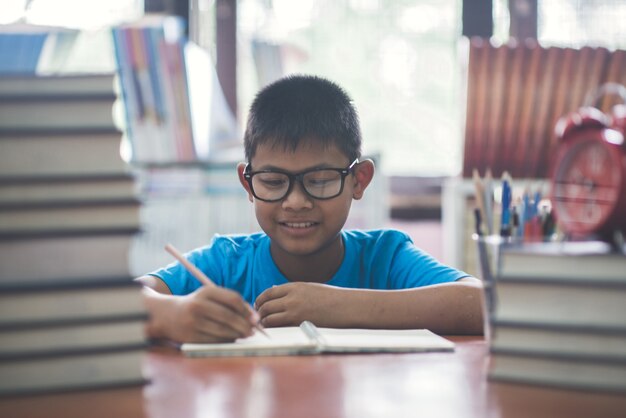 Niño feliz con lápiz escribiendo en el cuaderno.