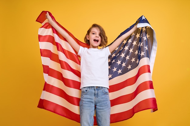 Niño feliz linda chica con bandera americana en amarillo usa celebrar el día de la independencia