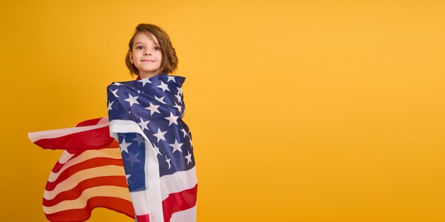 Niño feliz linda chica con bandera americana en amarillo usa celebrar el día de la independencia