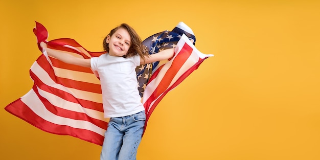 Foto niño feliz linda chica con bandera americana en amarillo