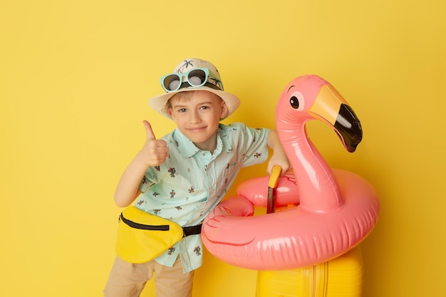 Niño feliz listo para unas vacaciones de verano Niño divirtiéndose contra el fondo amarillo Concepto de viaje y vacaciones para niños