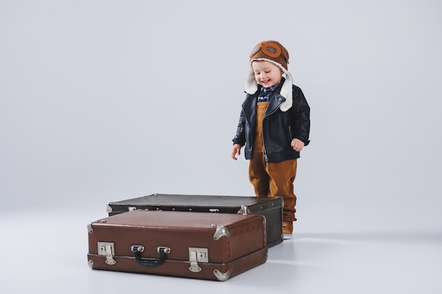 Niño feliz con una maleta marrón Retrato de un niño turista un niño con mono Pequeño viajero con una maleta