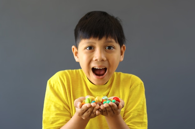 Niño feliz con las manos llenas de caramelos de colores surtidos