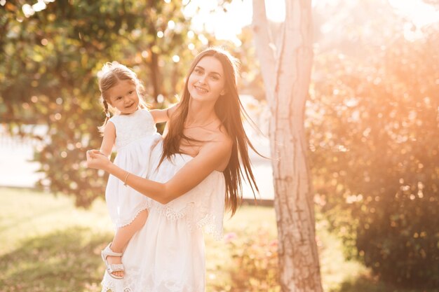 Niño feliz en manos de la madre en las luces del sol al aire libre