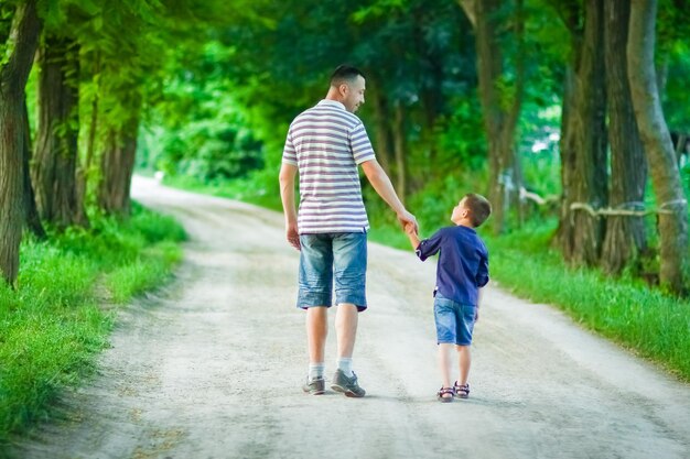 Un niño feliz y las manos de los padres en la naturaleza en el viaje del parque