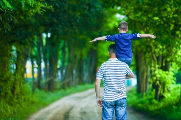 Un niño feliz y las manos de los padres en la naturaleza en el viaje del parque