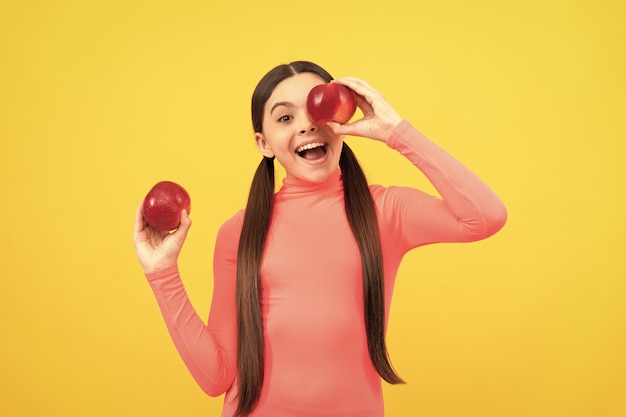 Niño feliz con manzana roja sobre fondo amarillo vitaminas