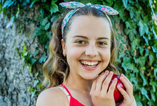 Foto niño feliz con mirada de belleza sonrisa con manzana roja madura en el jardín de verano sonriendo