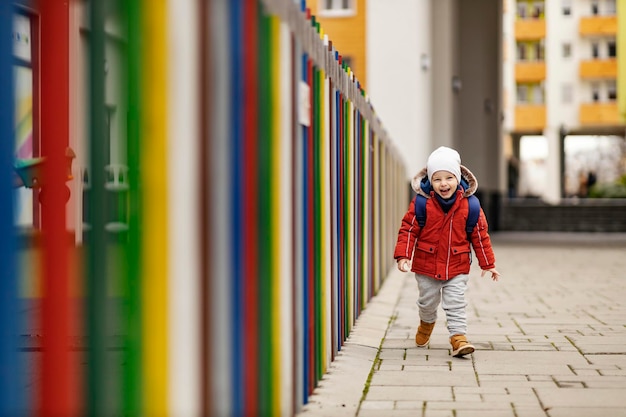 Un niño feliz con una mochila escolar corriendo al jardín de infantes