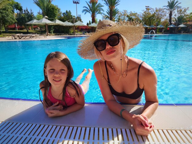 Niño feliz y mujer jugando en la piscina. Concepto de vacaciones de verano.