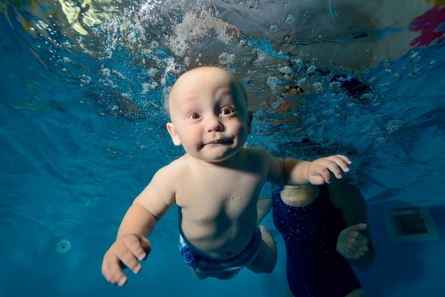 Niño feliz nadando bajo el agua en la piscina uno sobre un fondo azul.